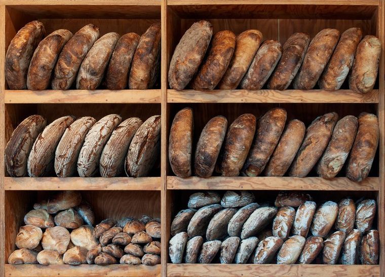 Wooden shelves filled with rows of assorted artisanal loaves of bread