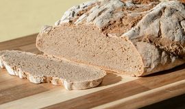 Loaf of rustic bread with sliced pieces on a wooden cutting board