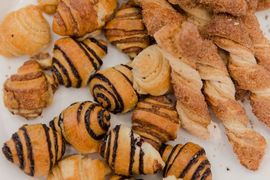 Assorted golden-brown pastries with chocolate drizzle arranged on a white surface