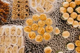 Assorted small pastries arranged in trays on a leopard-print surface