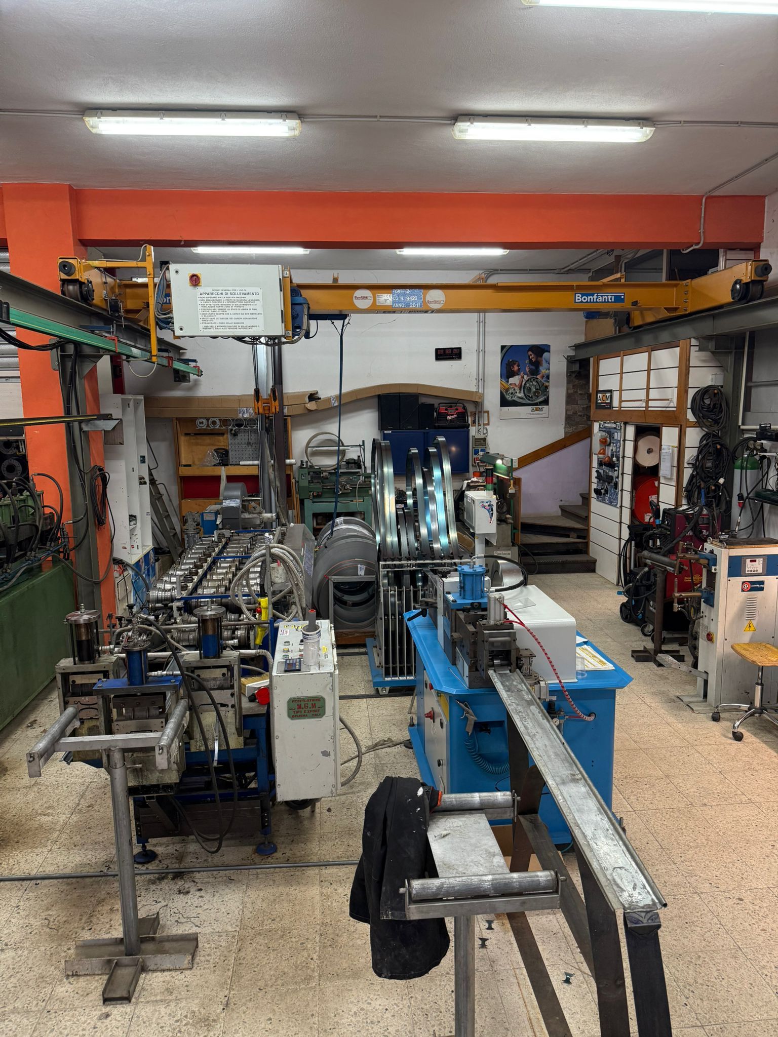 Officina con macchinari industriali, tra cui una piegatrice per tubi e attrezzature automatizzate.