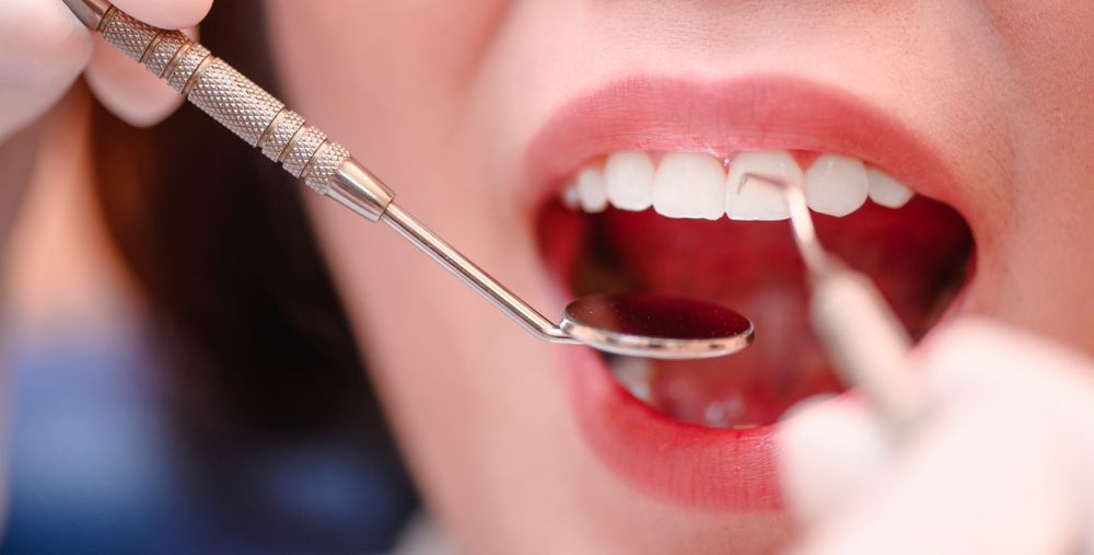 A Woman is Getting Her Teeth Examined by a Dentist— Graham Johnson Dental Surgery In Beresfield, NSW