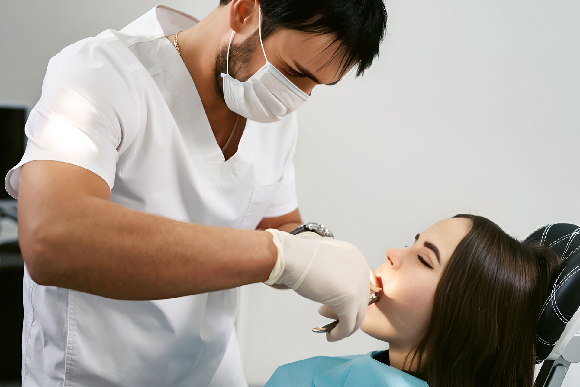 A Dentist is Examining a Woman 's Teeth in a Dental Chair — Graham Johnson Dental Surgery In Jesmond, NSW