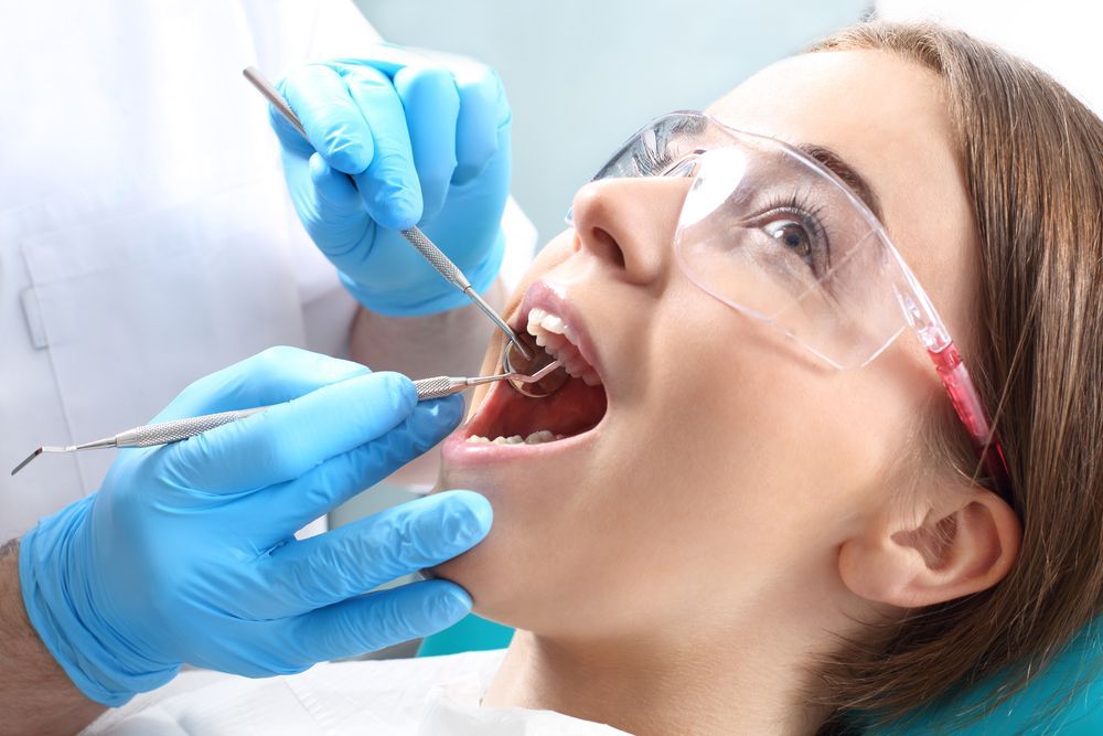 A Woman is Getting Her Teeth Examined by a Dentist — Graham Johnson Dental Surgery In Beresfield, NSW