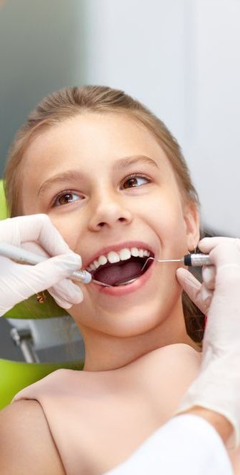 A Young Girl is Getting Her Teeth Examined by a Dentist — Graham Johnson Dental Surgery In Beresfield, NSW