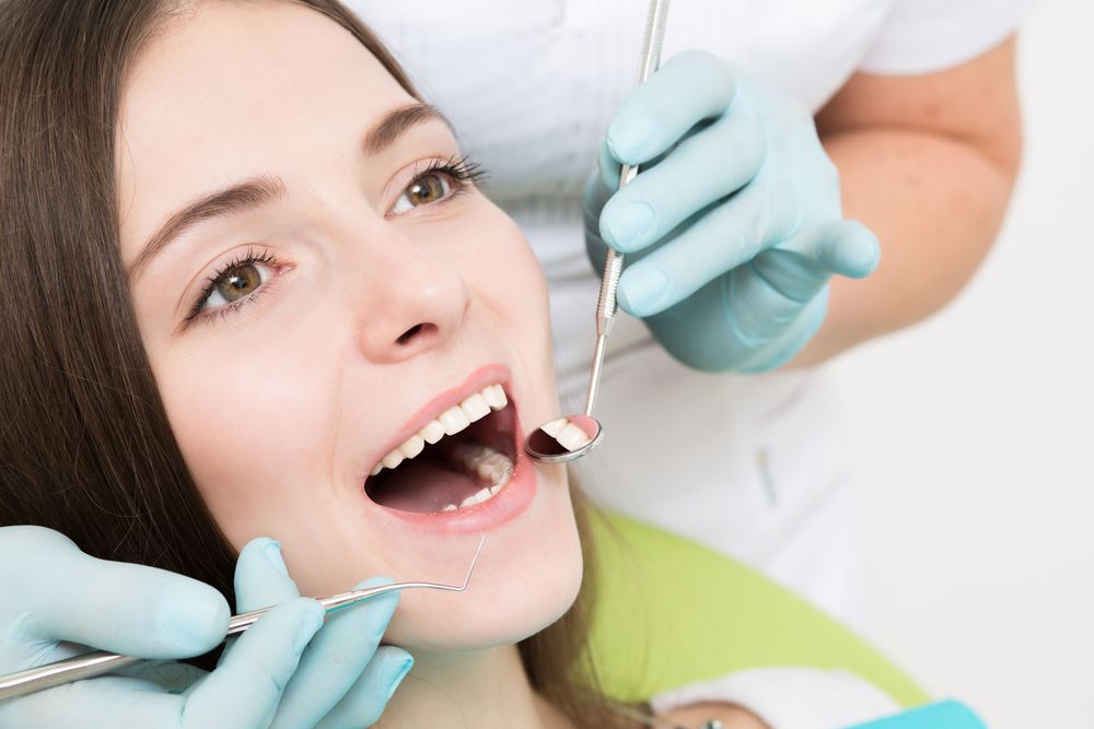 A Woman is Getting Her Teeth Examined by a Dentist — Graham Johnson Dental Surgery In Beresfield, NSW