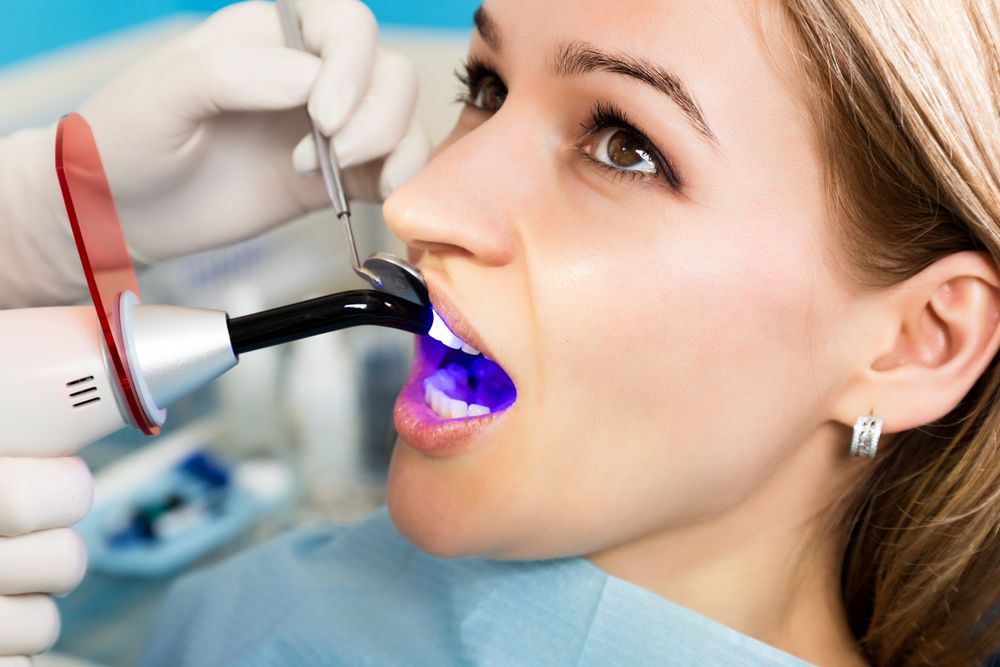 A Woman is Getting Her Teeth Whitened by a Dentist — Graham Johnson Dental Surgery In Beresfield, NSW