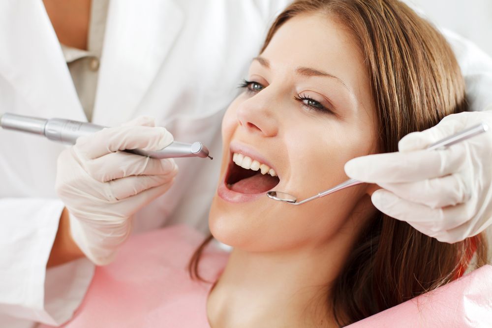 A Woman is Getting Her Teeth Examined by a Dentist — Graham Johnson Dental Surgery In Beresfield, NSW