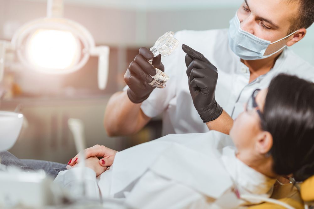 A Woman is Sitting in a Dental Chair While a Dentist Examines Her Teeth — Graham Johnson Dental Surgery In Jesmond, NSW