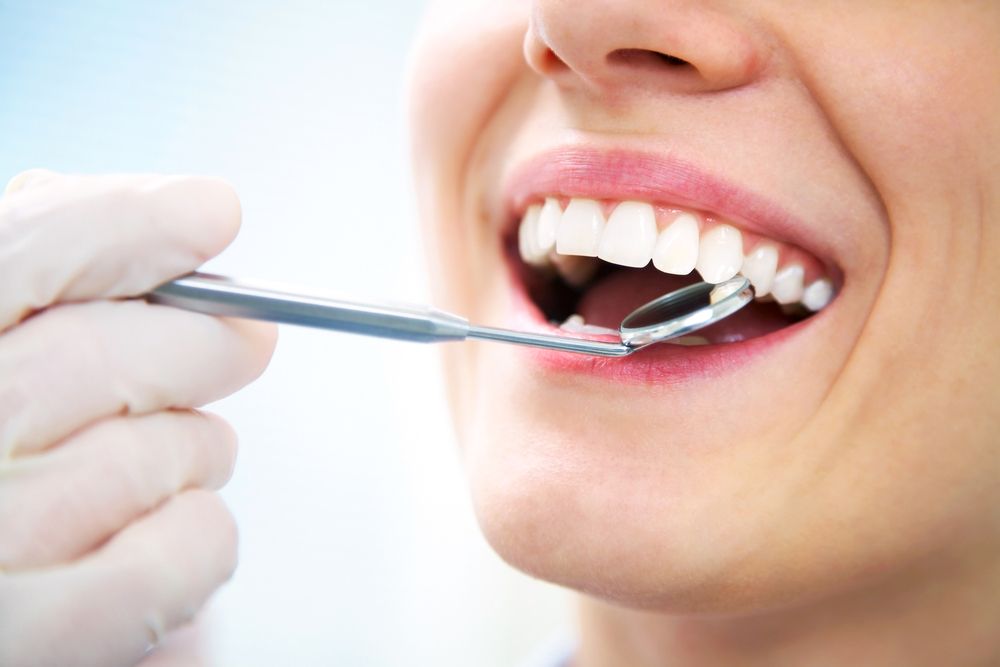 A Woman is Getting Her Teeth Examined by a Dentist — Graham Johnson Dental Surgery In Beresfield, NSW