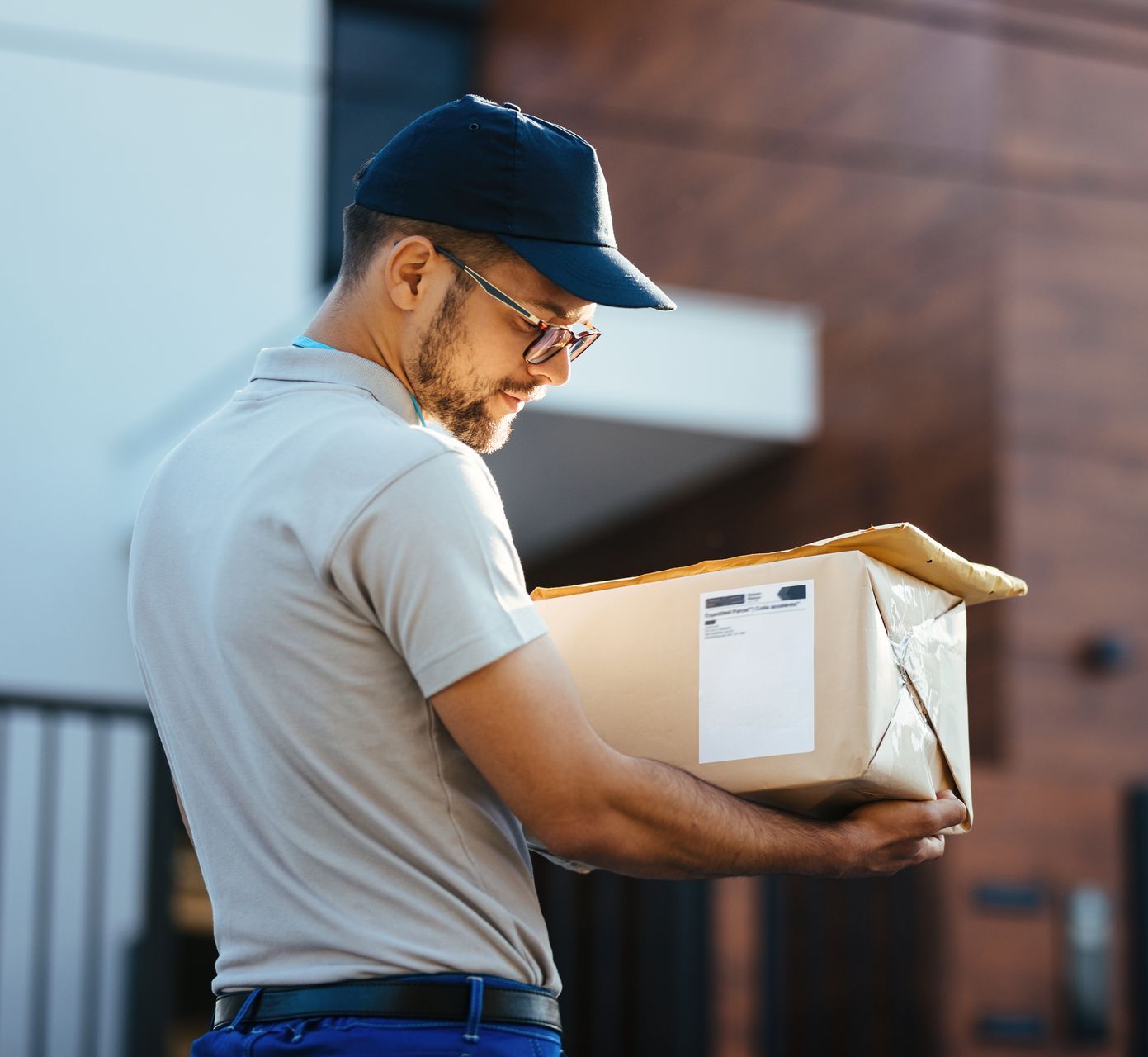 A Delivery Man is Holding a Cardboard Box in His Hands — Graham Johnson Dental Surgery In Beresfield, NSW