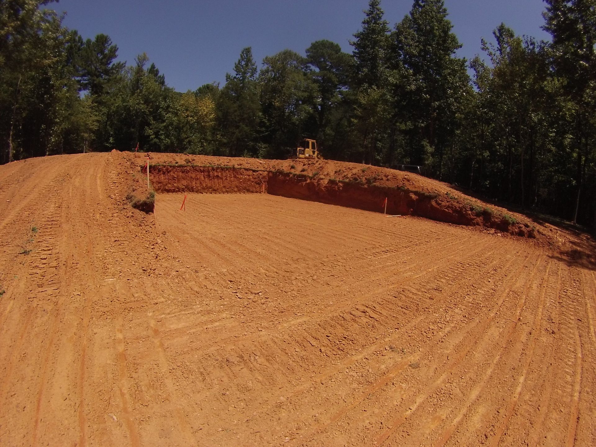 Dirt motocross jump on a sandy track with trees in the background