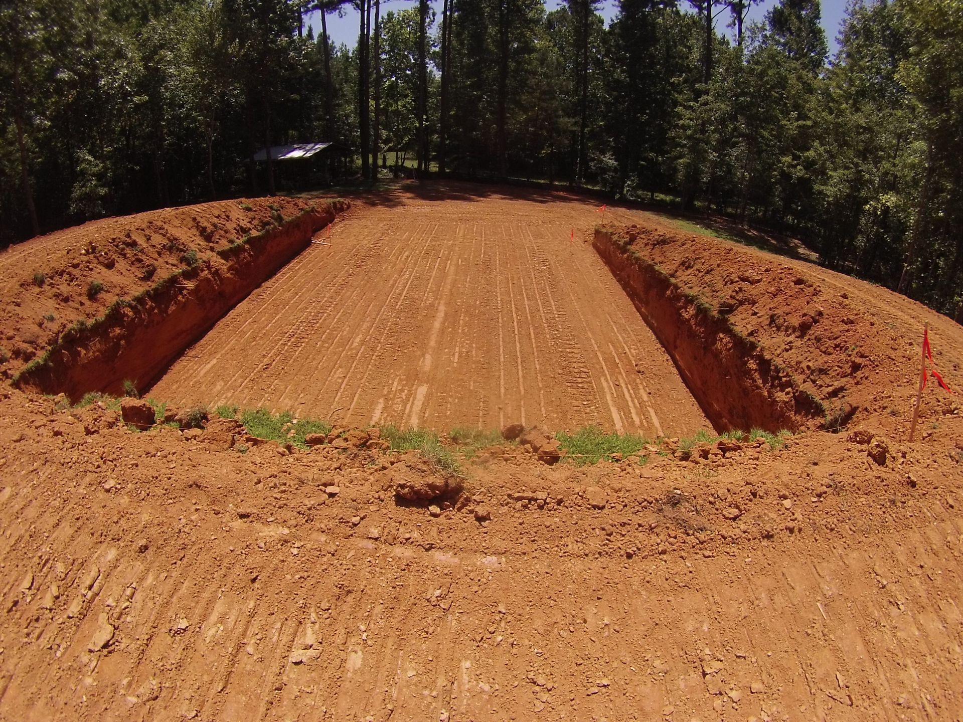 Dirt motocross jump ramp on a forest trail, with trees lining both sides.