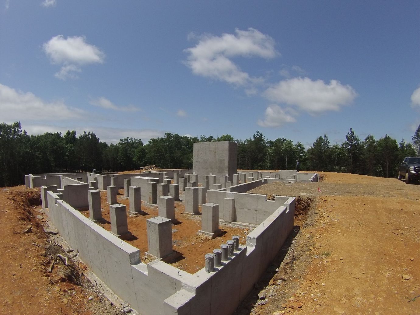 Heavy equipment backfilling a concrete foundation wall in North Georgia