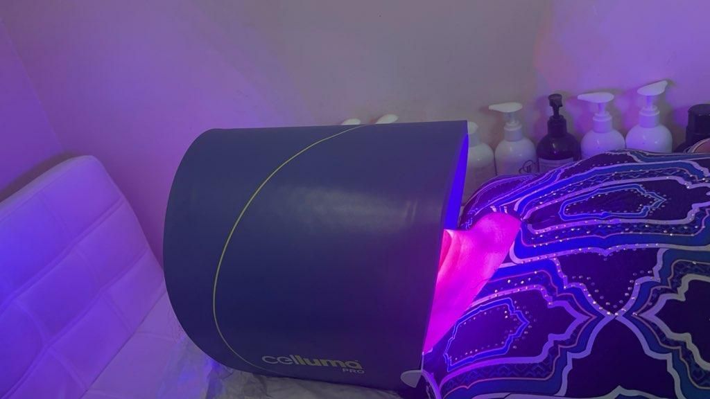Purple light from a therapy device illuminating a person's head and shoulders on a bed.