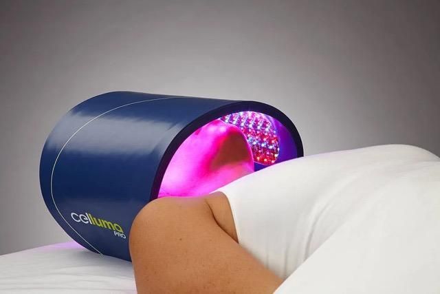Person receiving red light therapy treatment; device over head.