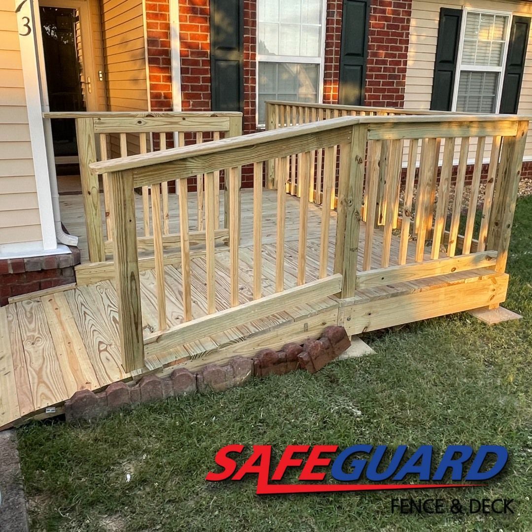 Wooden wheelchair ramp leading to a house entrance. Green grass and brick building in background. SafeGuard logo present.