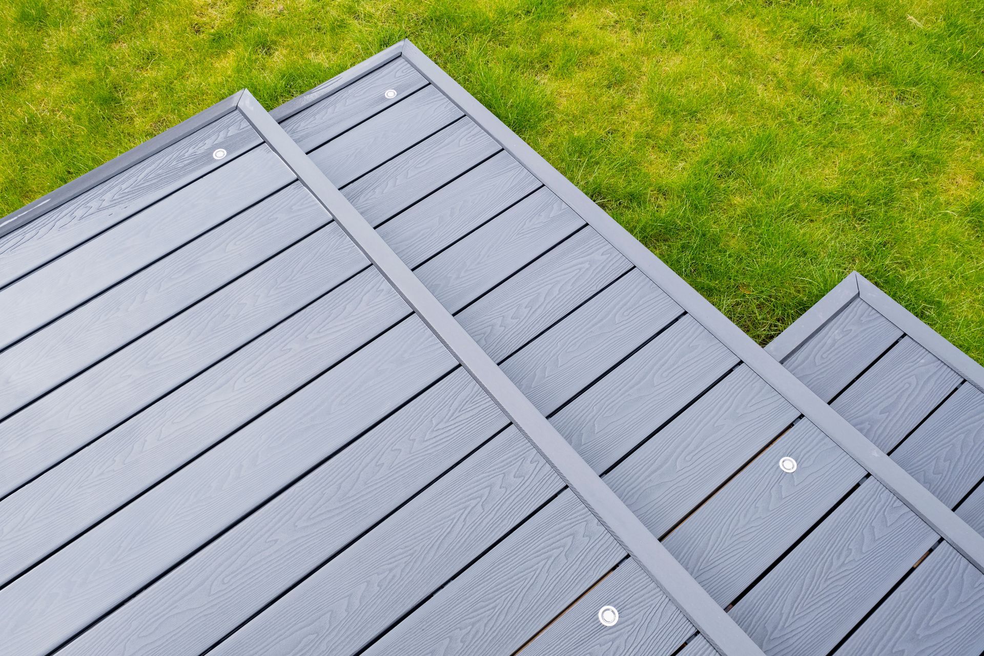 Grey composite deck stairs against green grass.