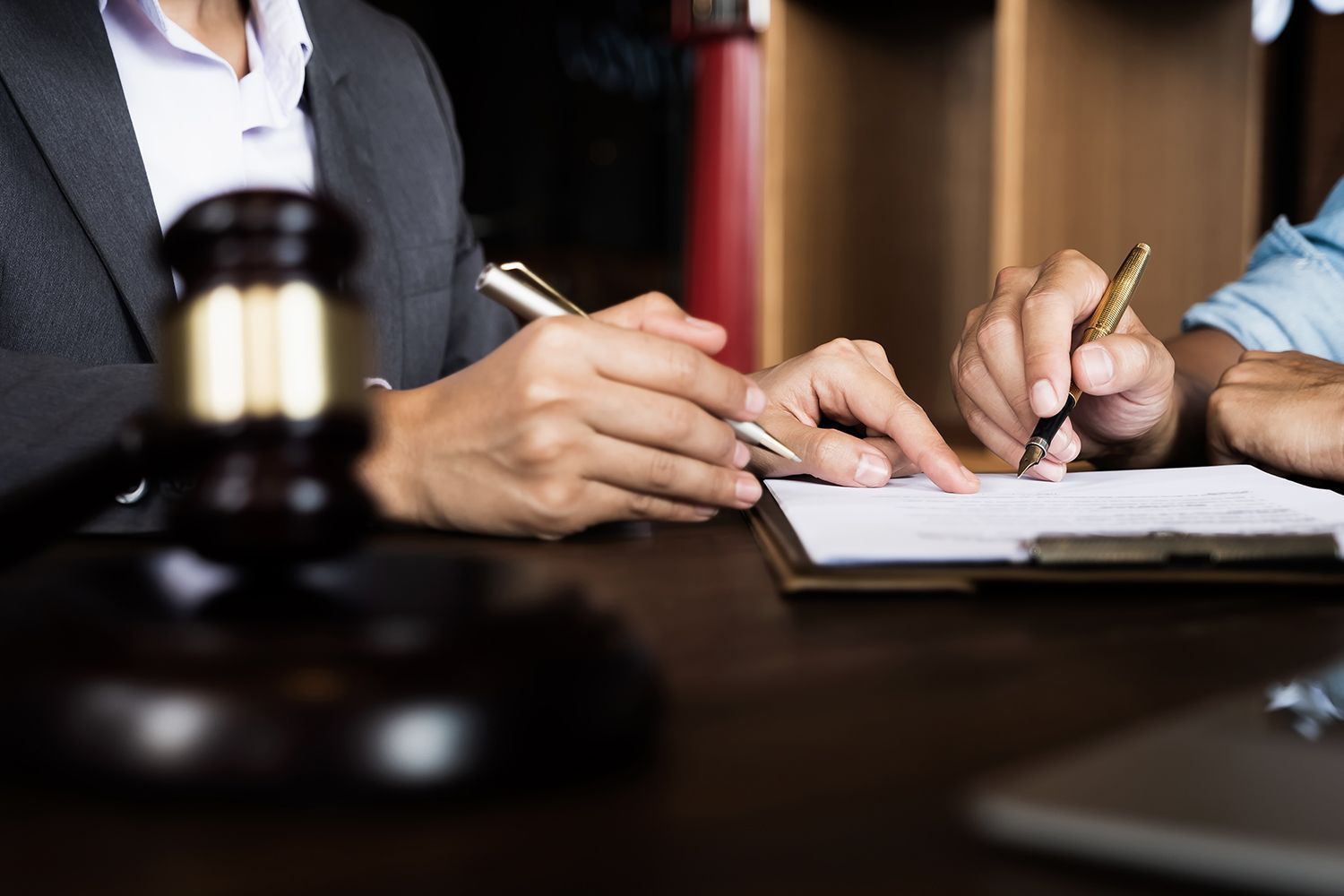Hands pointing at a document, beside a gavel, suggesting a legal consultation. Hands pointing at a document, beside a gavel, suggesting a legal consultation.