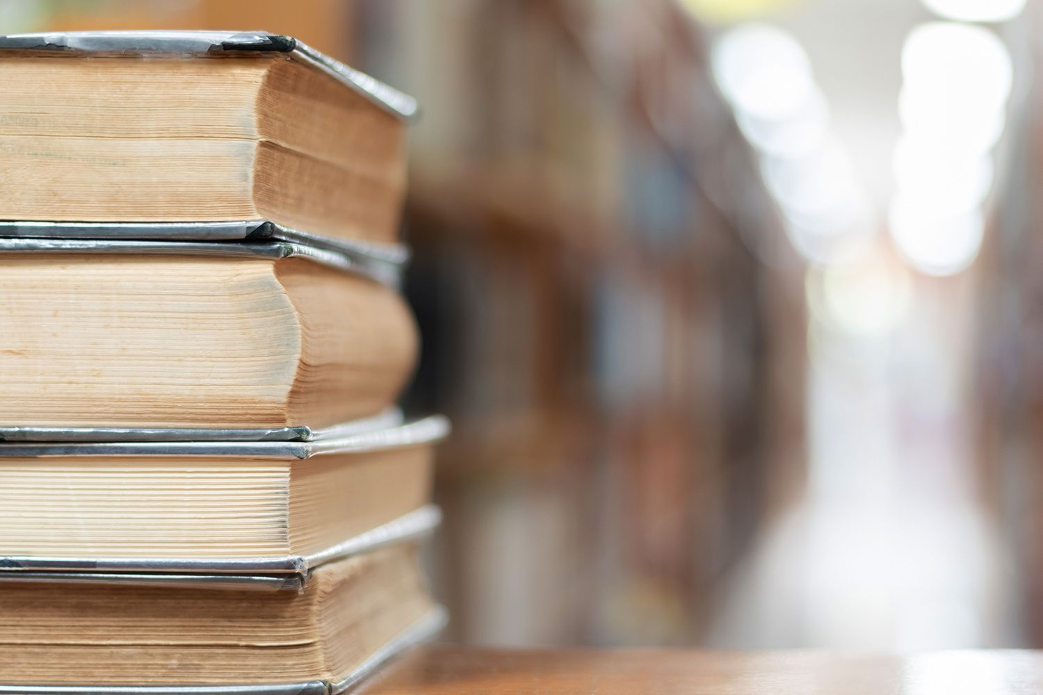 Stack of books on a table with a blurred library background. Stack of books on a table with a blurred library background.
