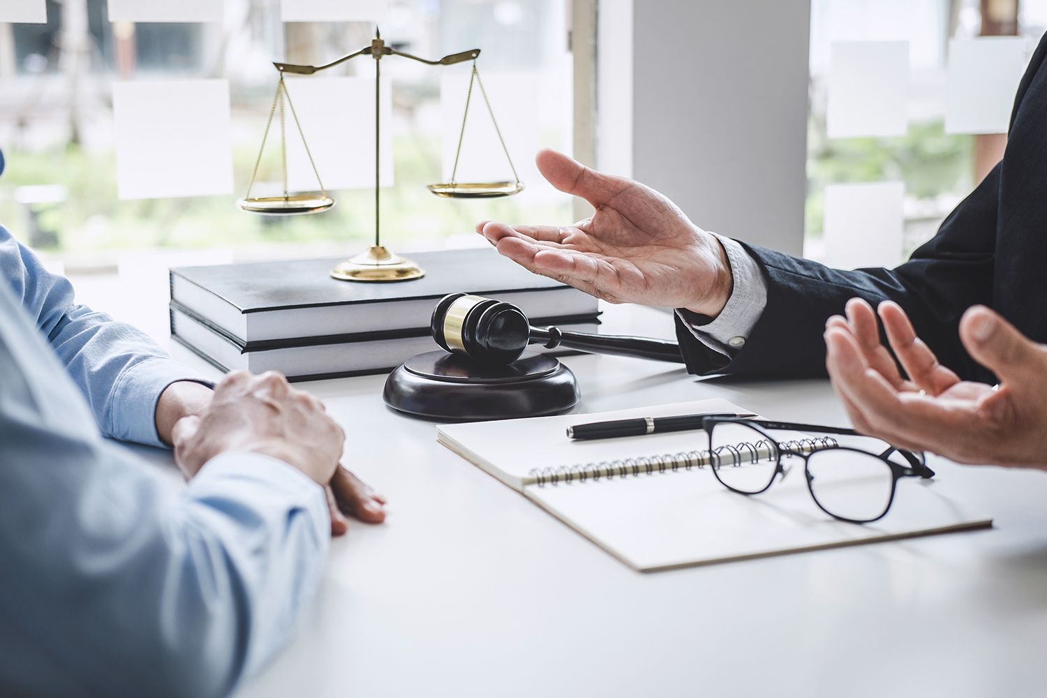 Lawyer explains something to a client, scales of justice and gavel on desk. Lawyer explains something to a client, scales of justice and gavel on desk.