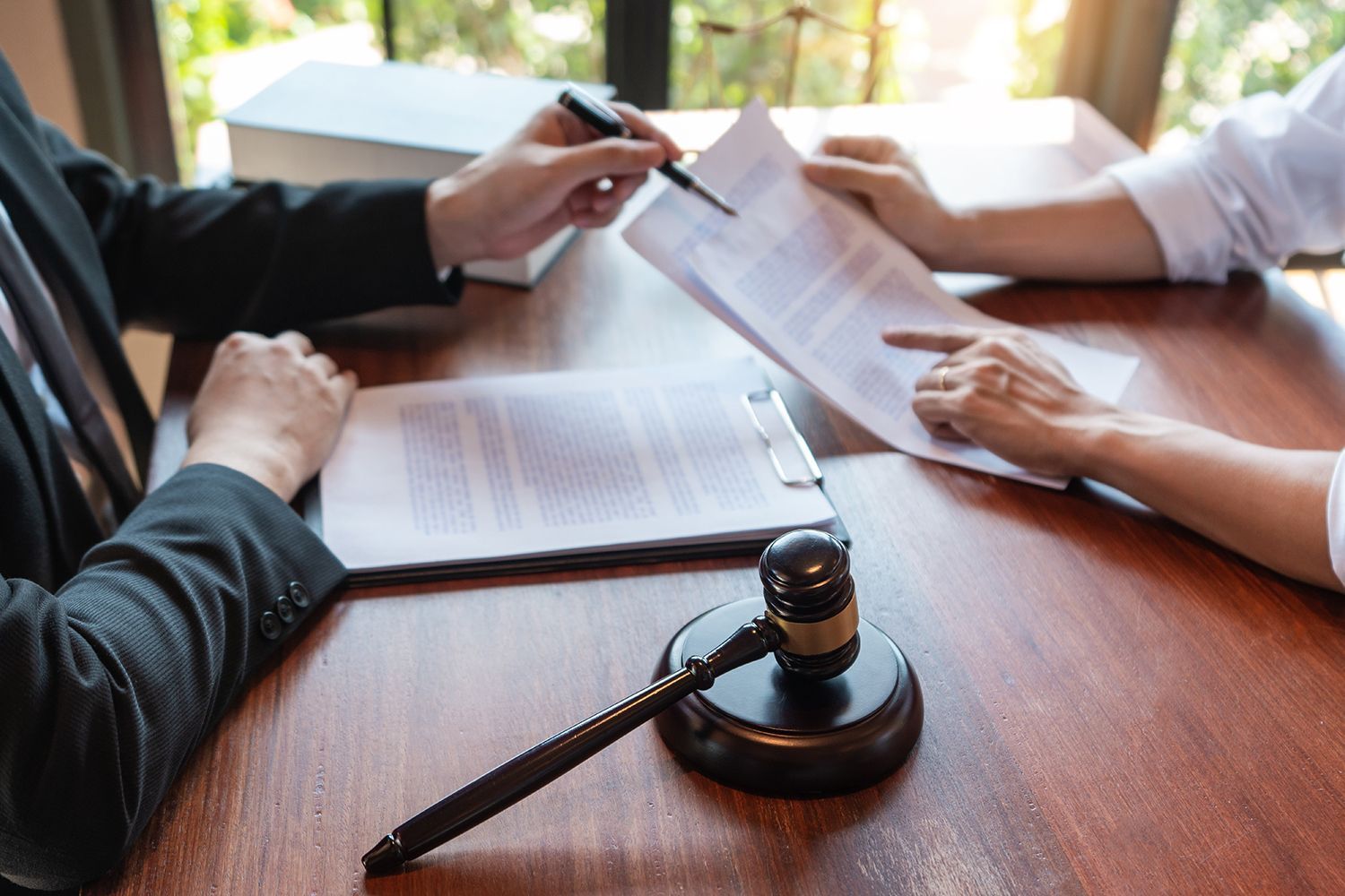 Lawyer pointing at documents with client; gavel on the table. Lawyer pointing at documents with client; gavel on the table.