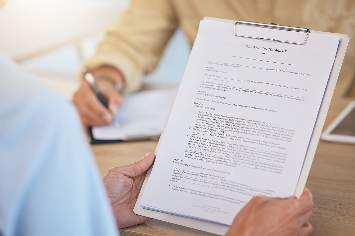 Person holding a clipboard with document while another person writes; office setting. Person holding a clipboard with document while another person writes; office setting.