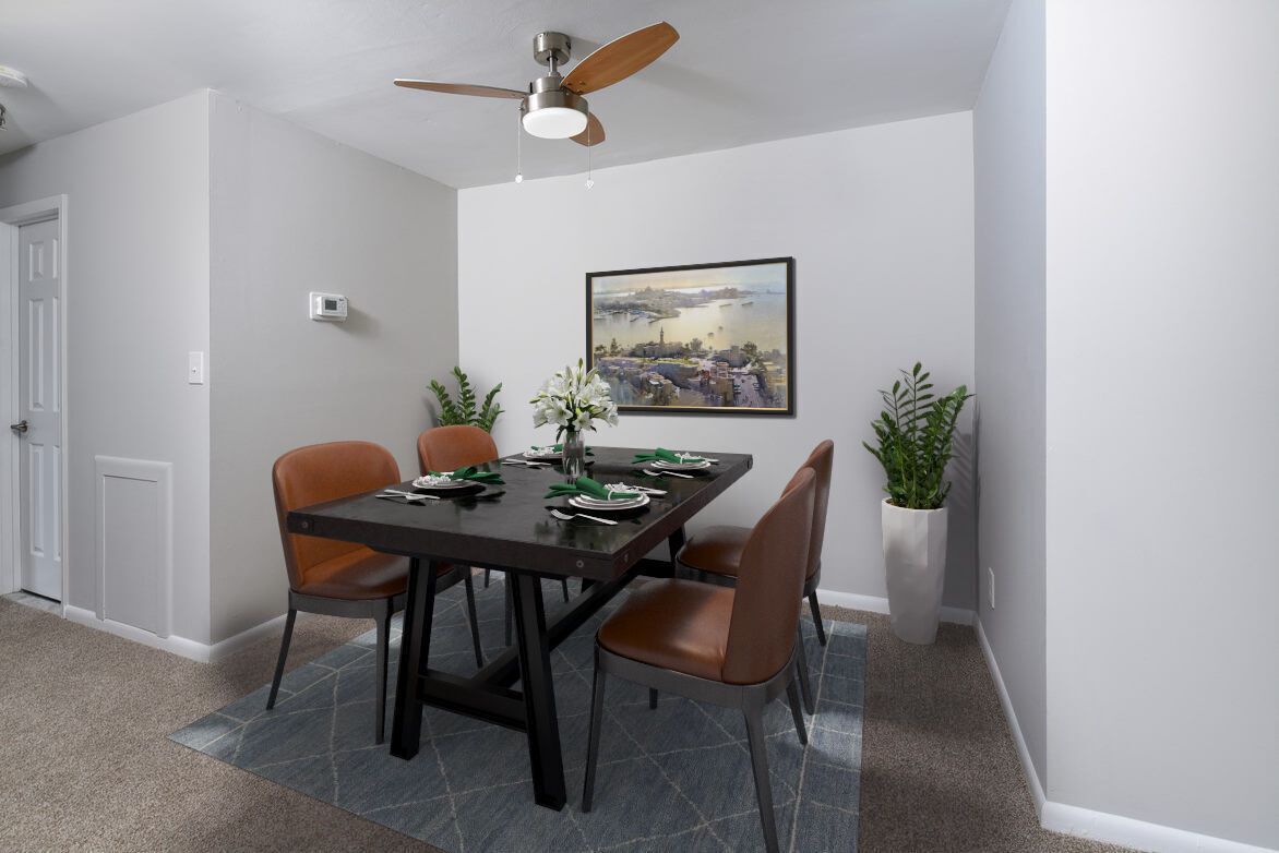 Dining area in apartment: black dining table, four brown chairs, ceiling fan, wall art, and plants.