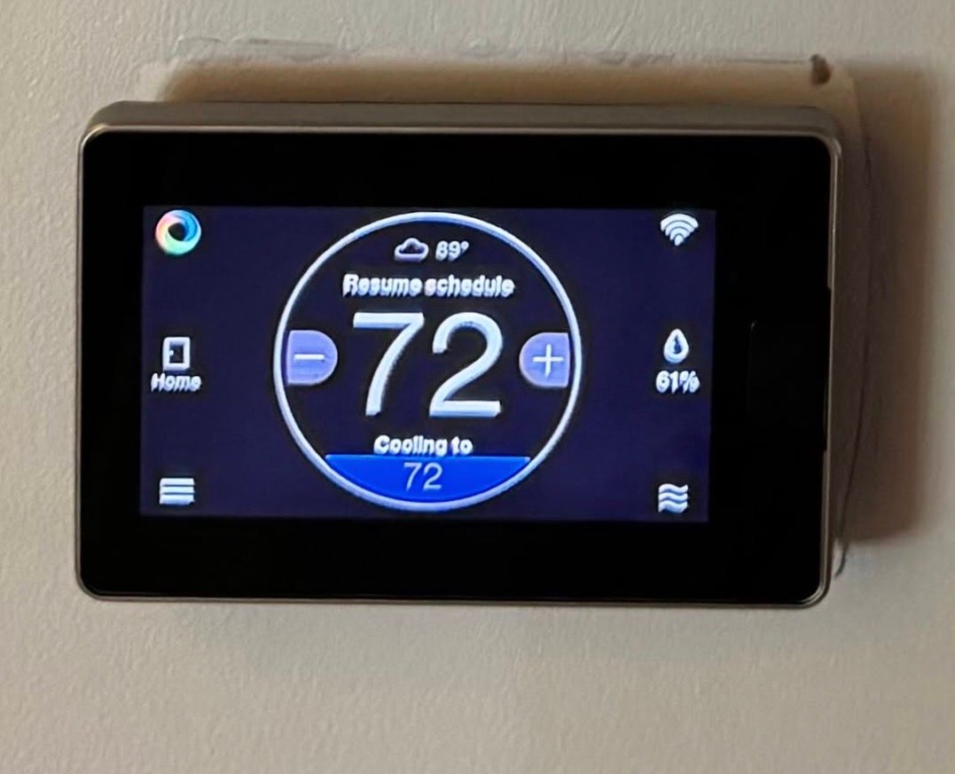 Wall-mounted digital thermostat displaying 72°F on a dark screen with blue accents.