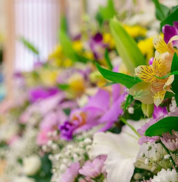 Ramo colorido de flores moradas, blancas y amarillas con hojas verdes desenfocadas suavemente