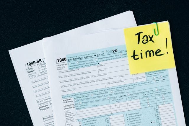 Documents with a yellow paper clipped to them that reads 