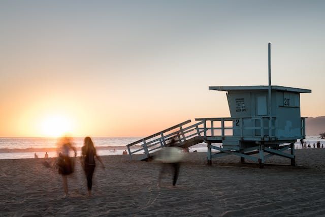 a beach at sunset with people carrying surfboards