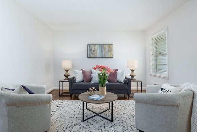 a white living room with a two seater couch and two arm chairs