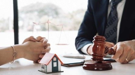a contract a gavel and a home figurine on desk