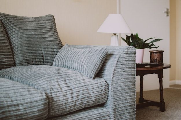 grey/blue couch with dark wood side table and white lamp