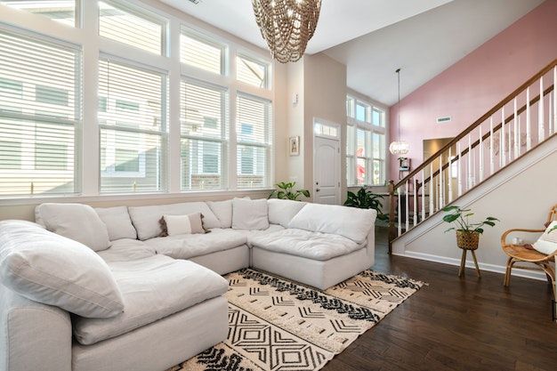 living room with white U-shaped couch, large picture window and pink accent wall