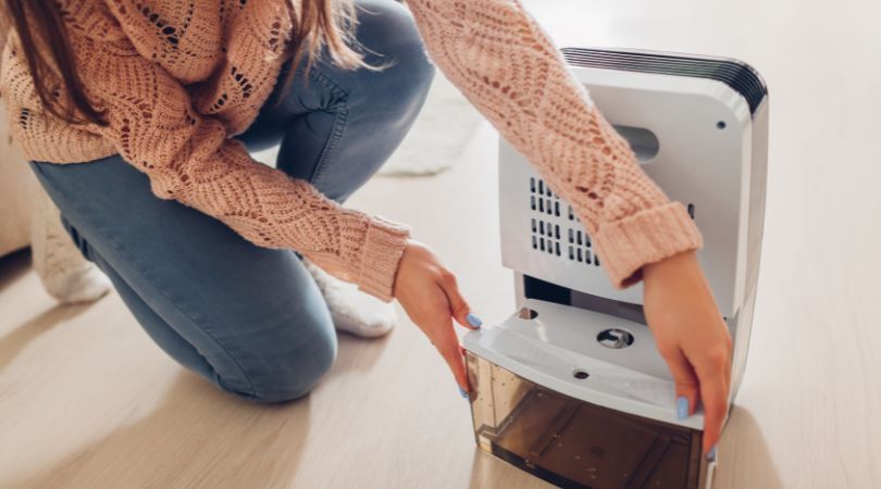 person checking water levels in their dehumidifier