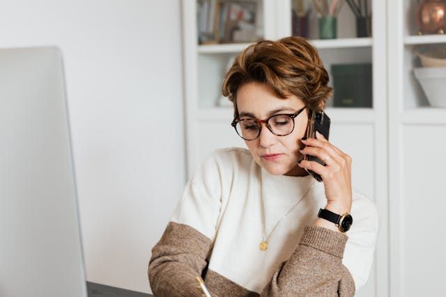 person talking on the phone and taking notes