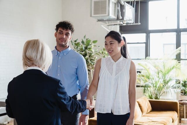 two tenants shaking hands with a landlord during a property tour