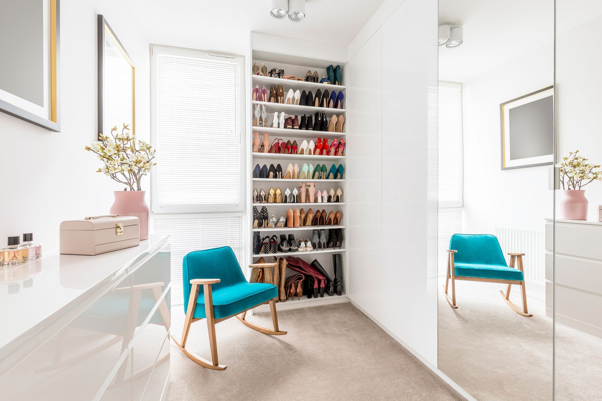 A section of a custom closet with drawers, show storage, and a window with blinds