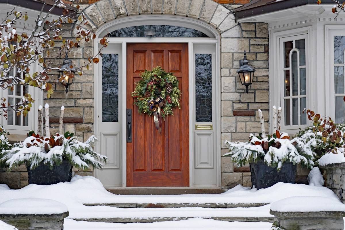 A luxurious holiday-themed front door with sidelights on the side and a snow-covered landscape at Alton Bay Blinds near Hampton, NH
