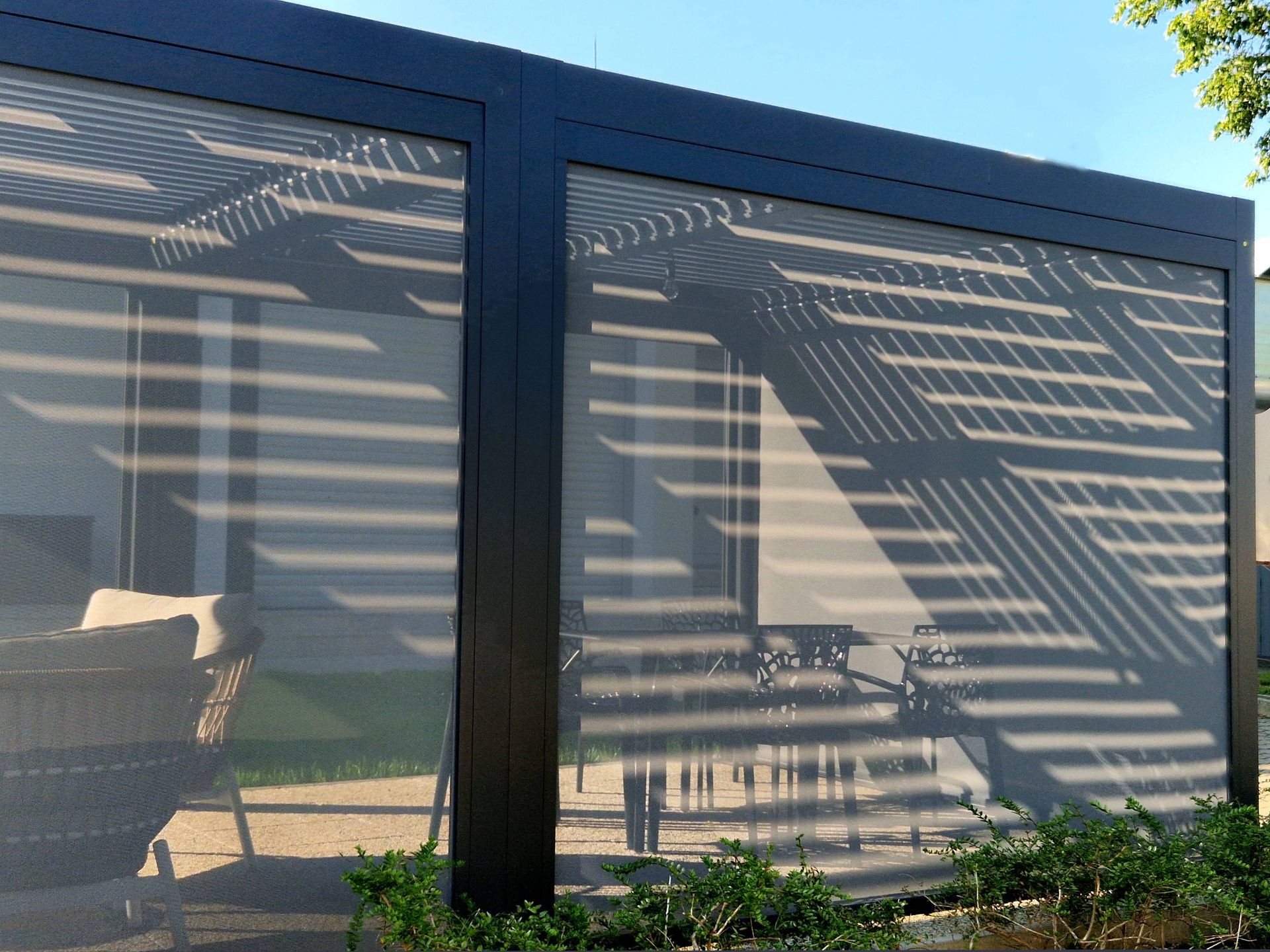 A motorized outdoor screen on a home's patio with outdoor furniture placed inside the area at Alton