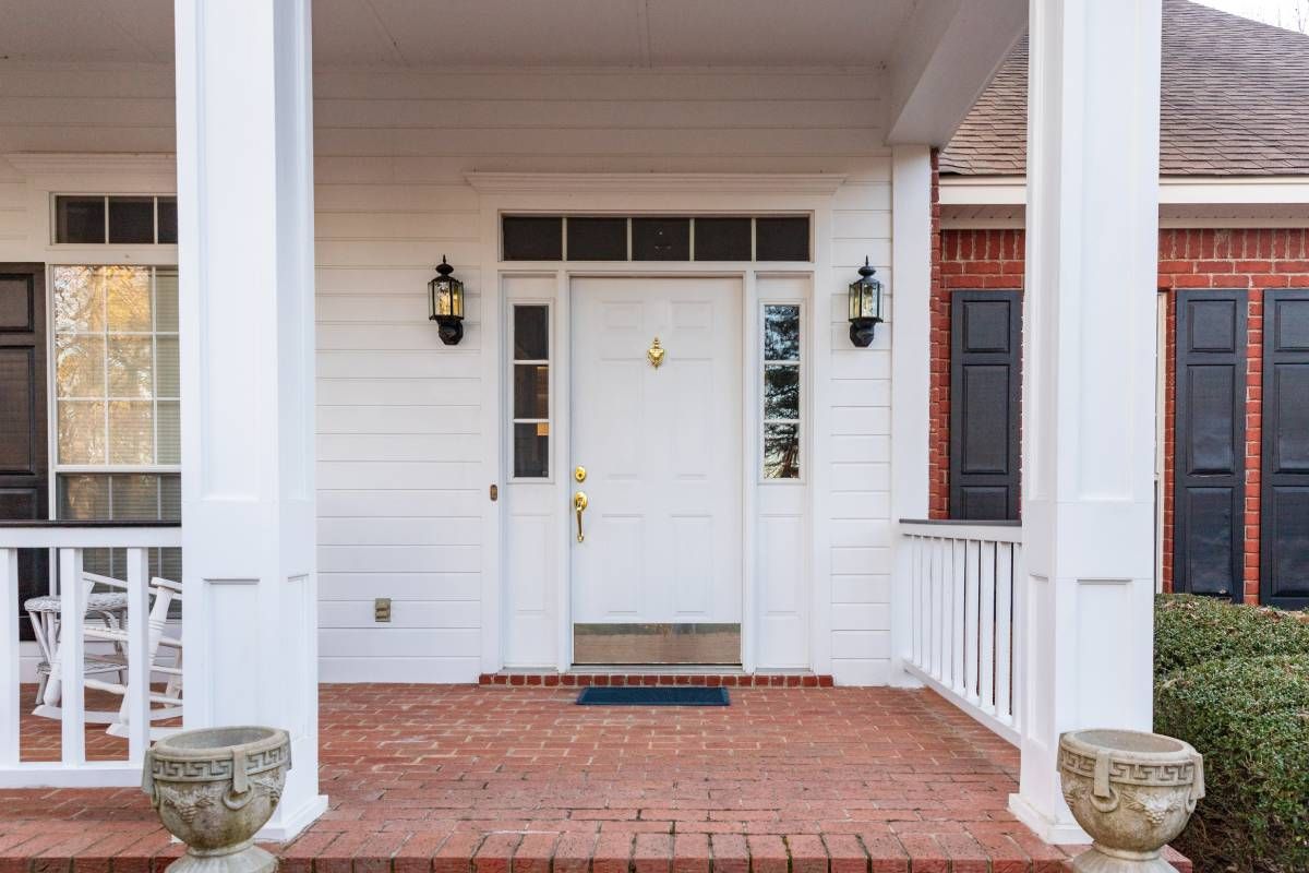 White front door with side windows on a residential porch with brick flooring