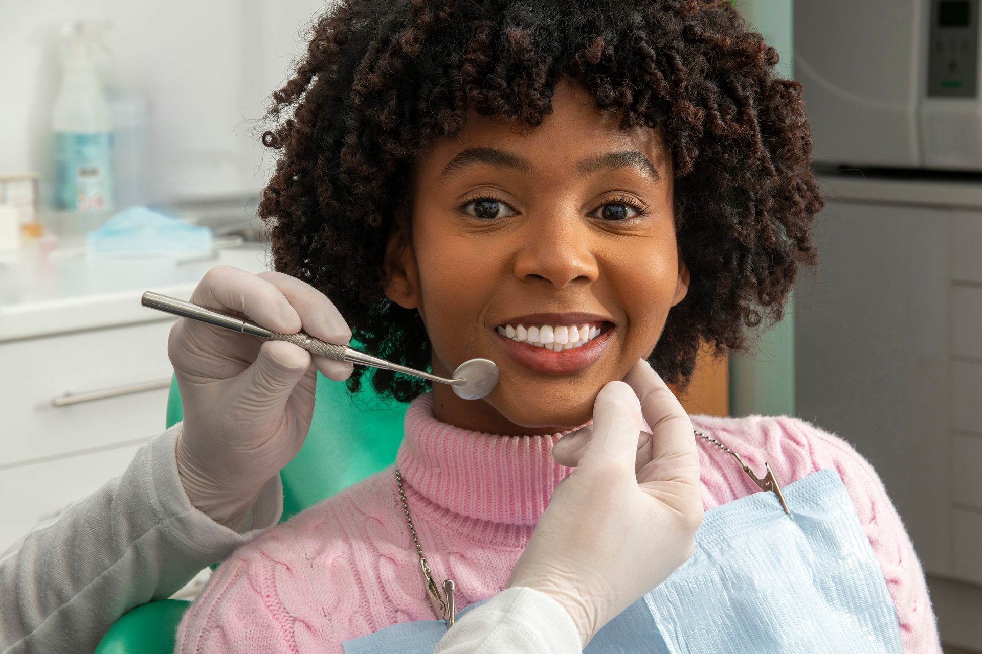 Dentist examining teeth of smiling patient in dental clinic.