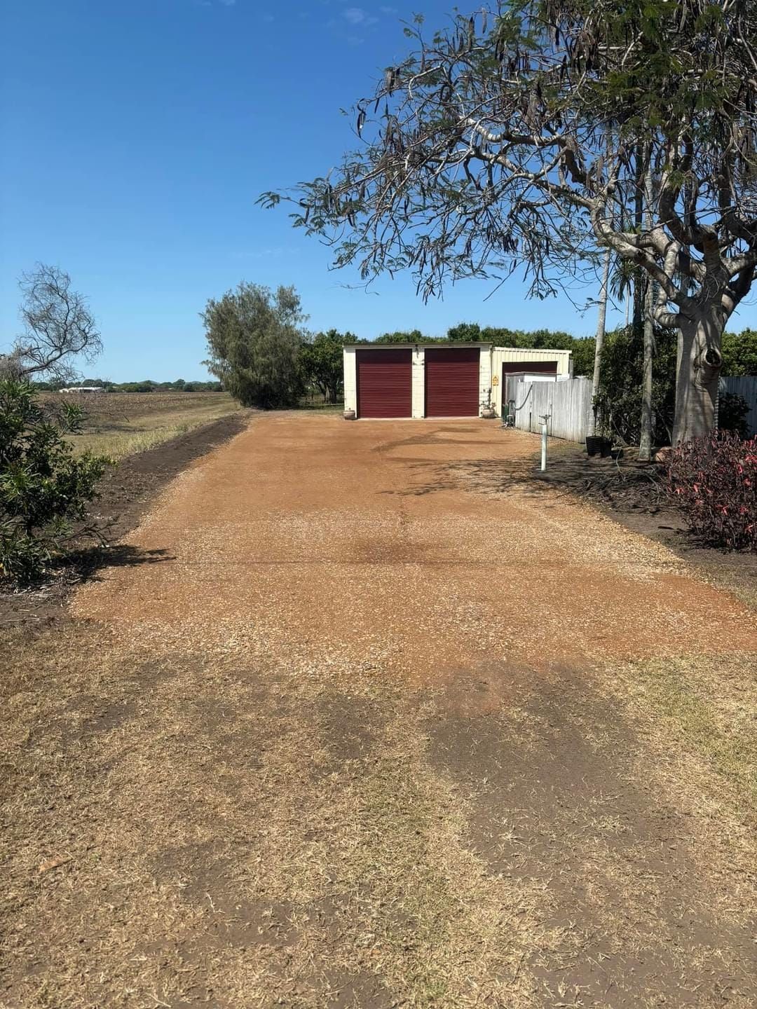 Gravel Driveway Leading to a Garage With Red Doors — DJ Brazil Pty Ltd in Bowen, QLD