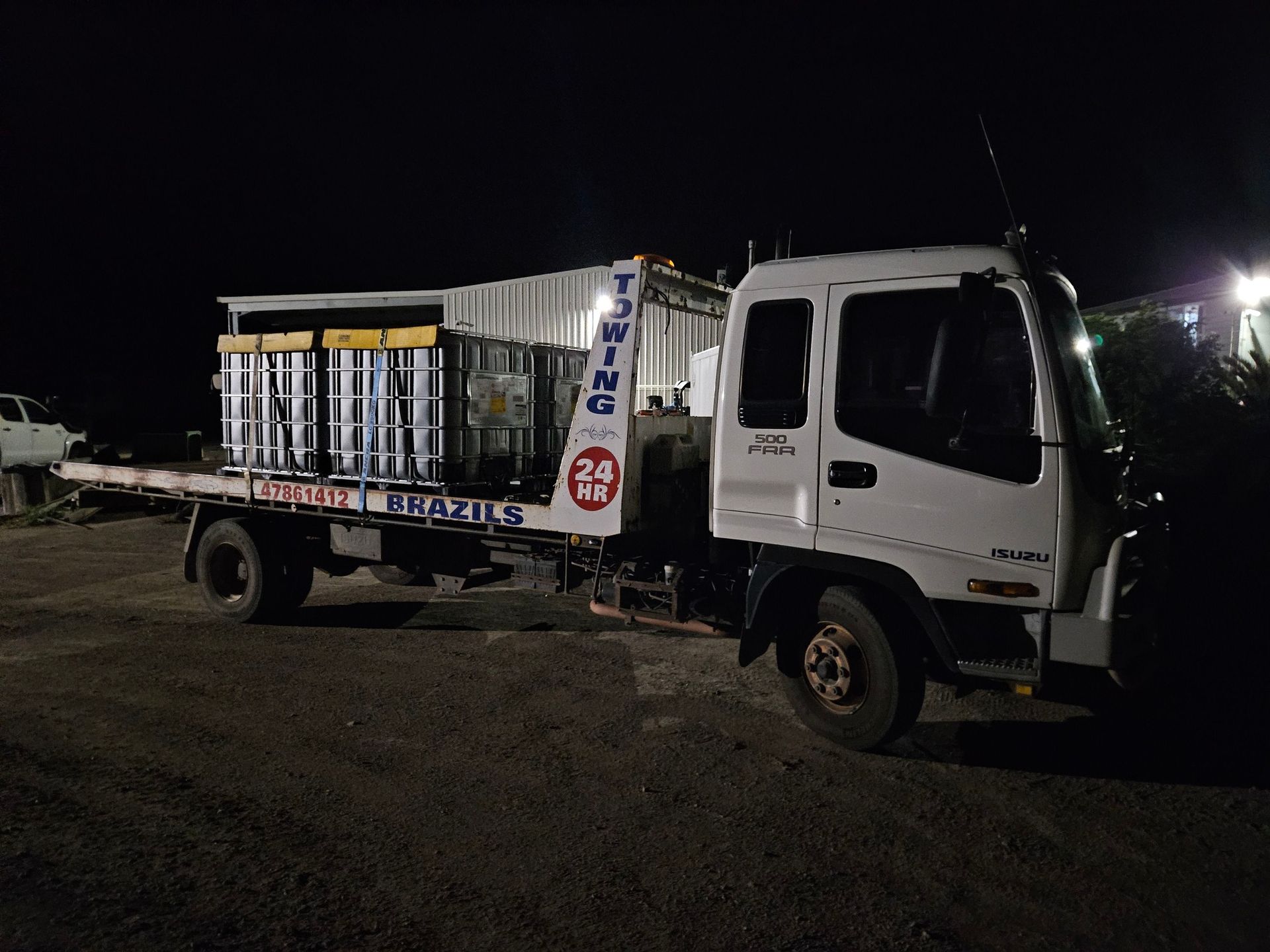 White truck with cargo bed at night, hauling large containers - DJ Brazil earthmoving, truck and tilt tray hire, Bowen QLD