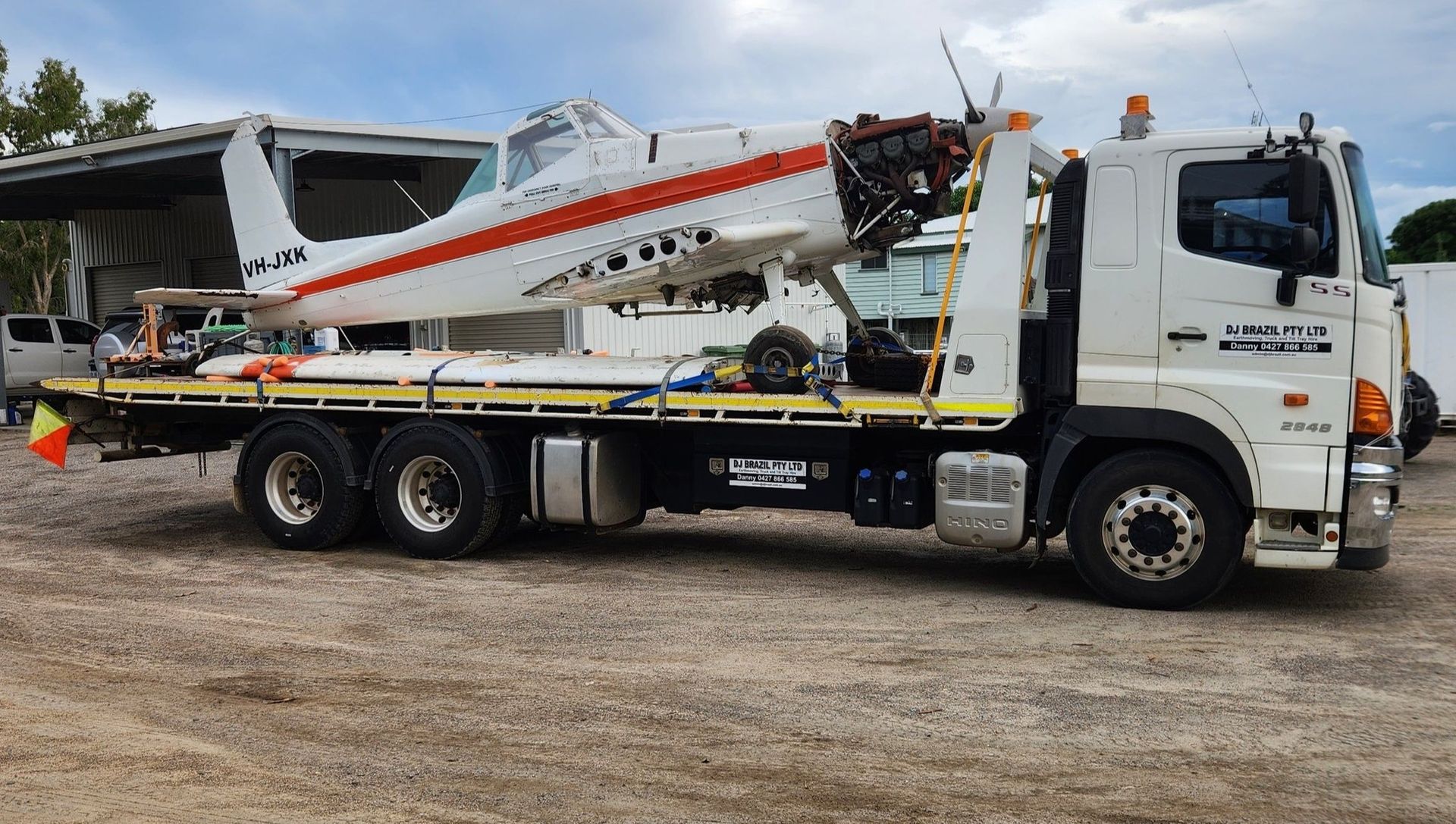Bobcat skid steer and mini-excavator secured on a flatbed truck travelling on a road— DJ Brazil Pty Ltd in Bowen, QLD