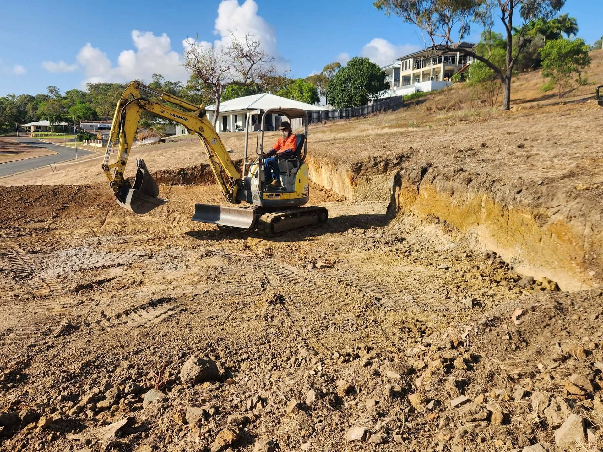 Yellow excavator digging on a construction site; operator in the cab.