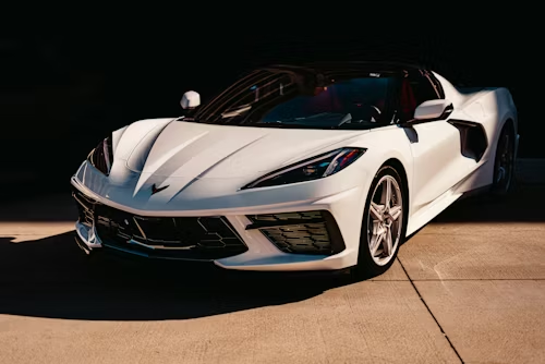 White sports car on display under spotlights in a dark showroom