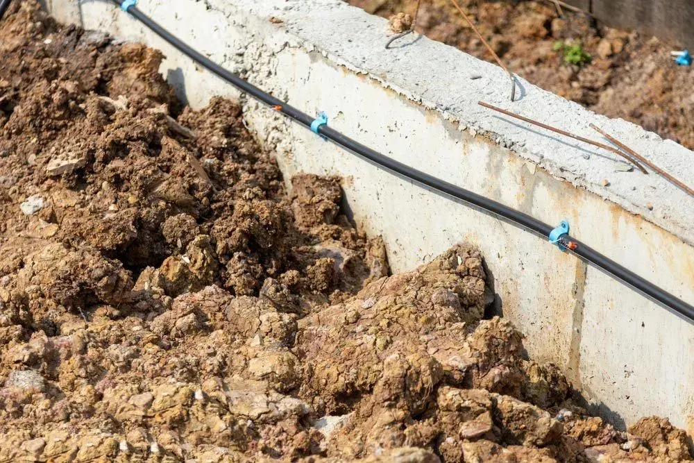 A hose is connected to a concrete wall next to a pile of dirt — Border Pest Control In Albury, NSW